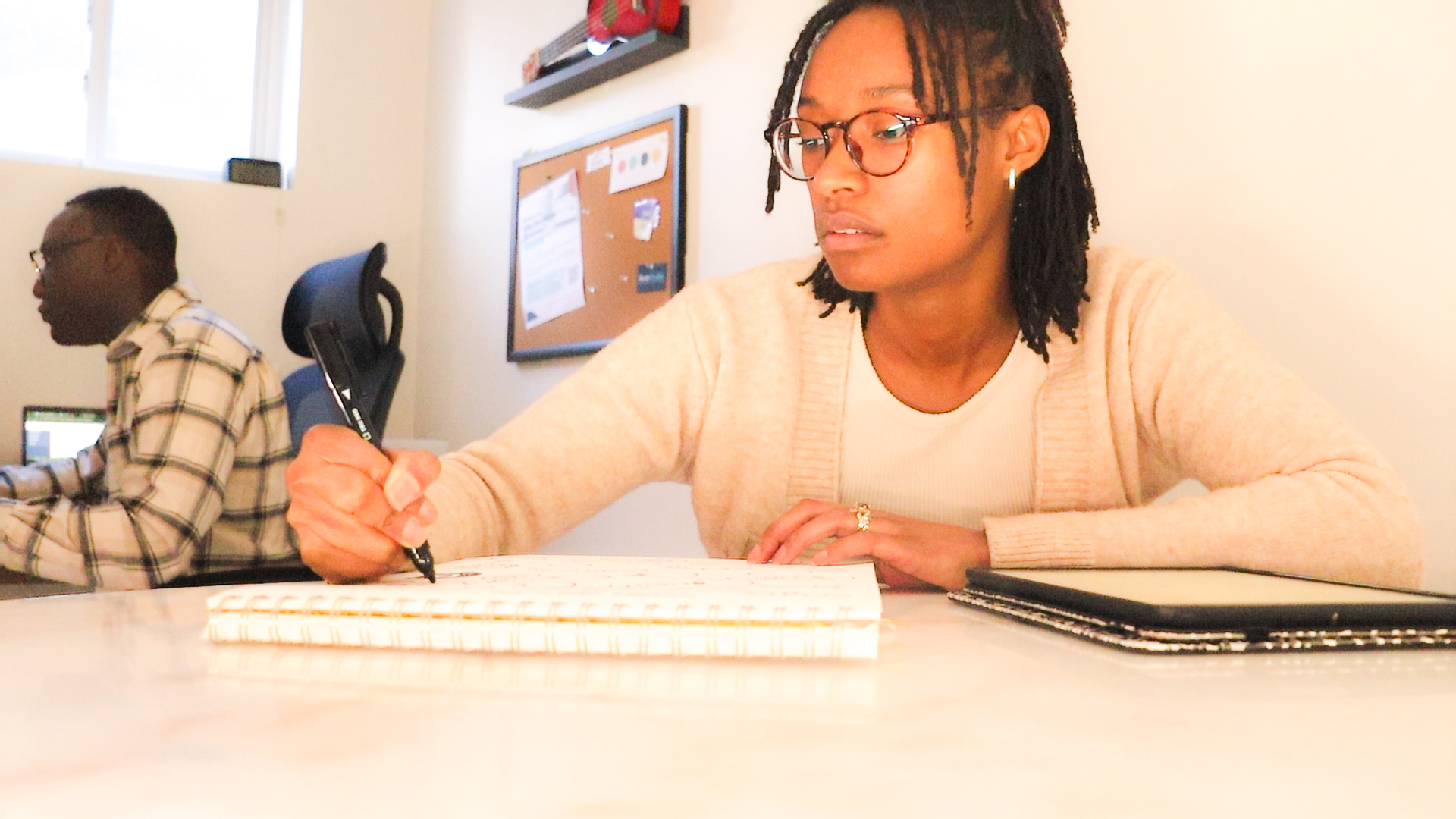 Deilia Ikuomenisan sketching a logo while Toyin Ikuomenisan codes in the background
